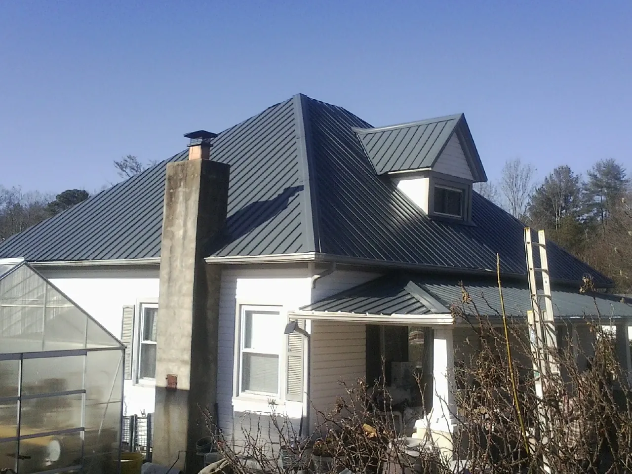Dark blue standing seam metal roof on a white farmhouse with dormer — Slate & Tile Roof Repair by Roofing Brothers in Holyoke