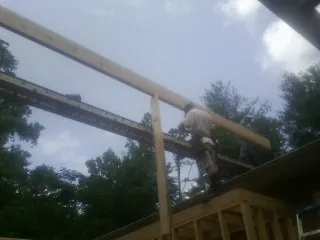 Carpenter setting a ridge beam over a new addition frame — Ice Dam Removal by Roofing Brothers in Holyoke