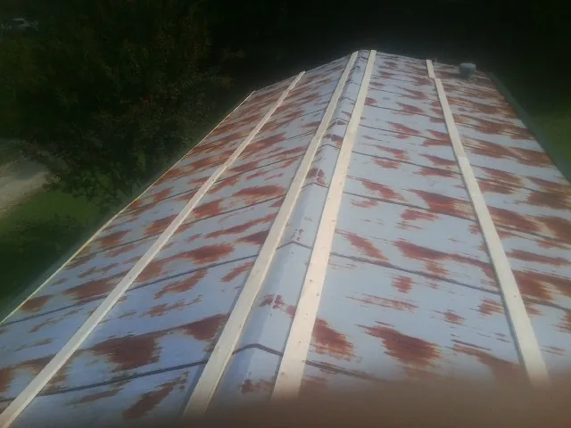 Rusted metal roof panels with new wood purlins before replacement — Storm Damage Roof Repair in Holyoke by Roofing Brothers