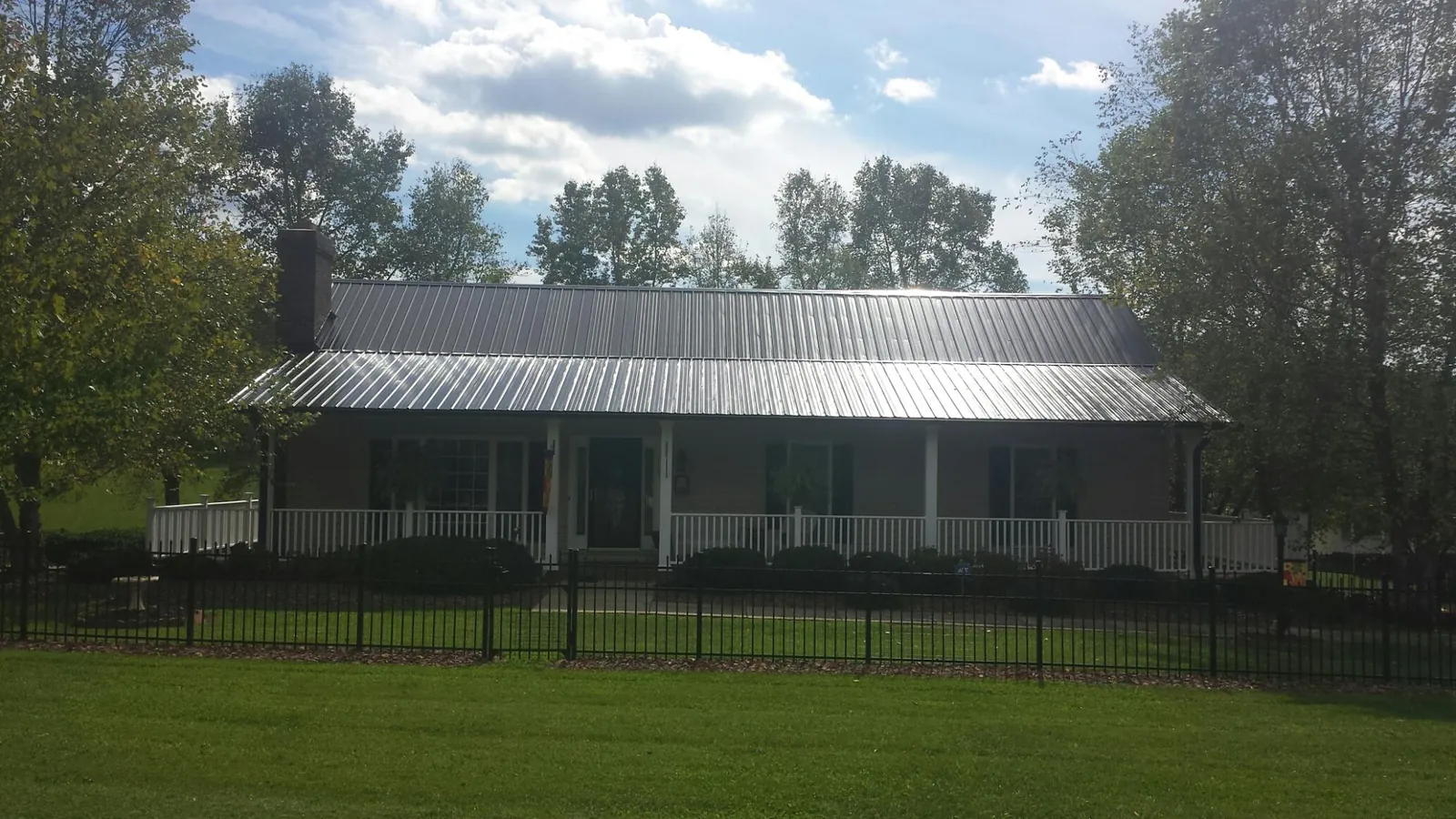 Gray metal roof on a brick ranch with a full width front porch — Gutter Guard Installation work by our crew in Holyoke