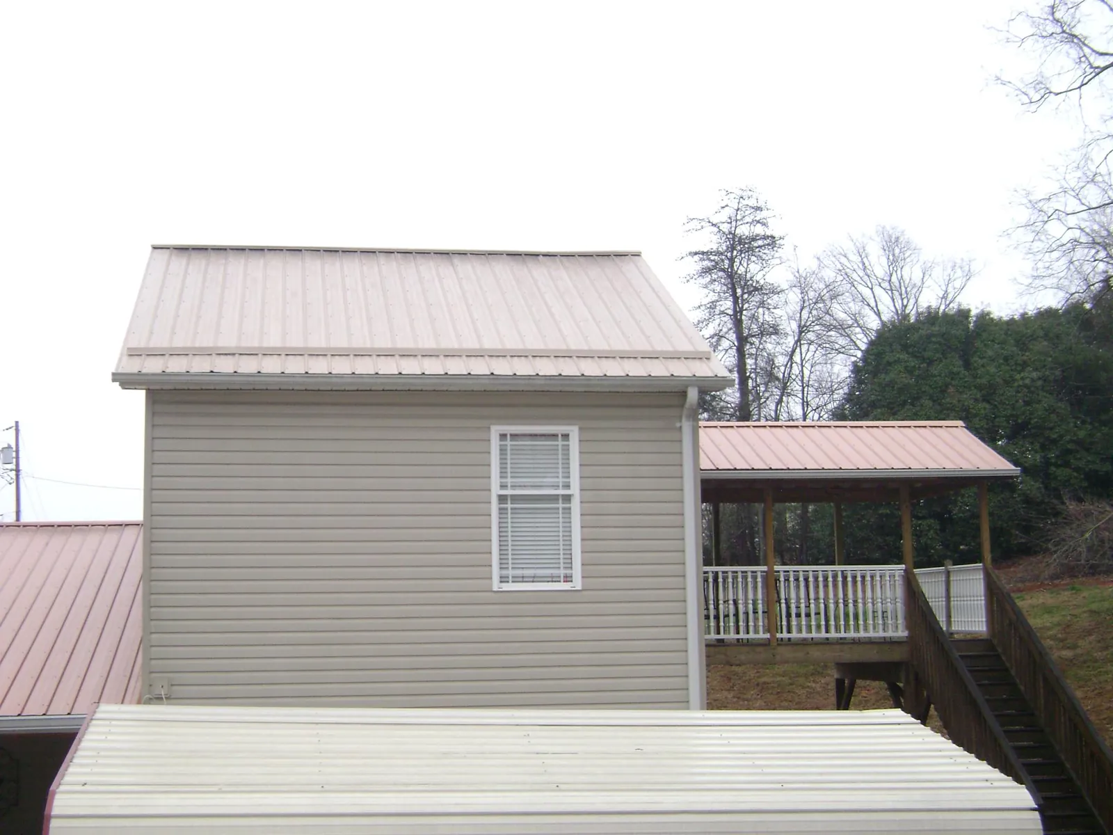 Tan metal roofs on a two story addition and attached porch, from a Roof Replacement job in Holyoke