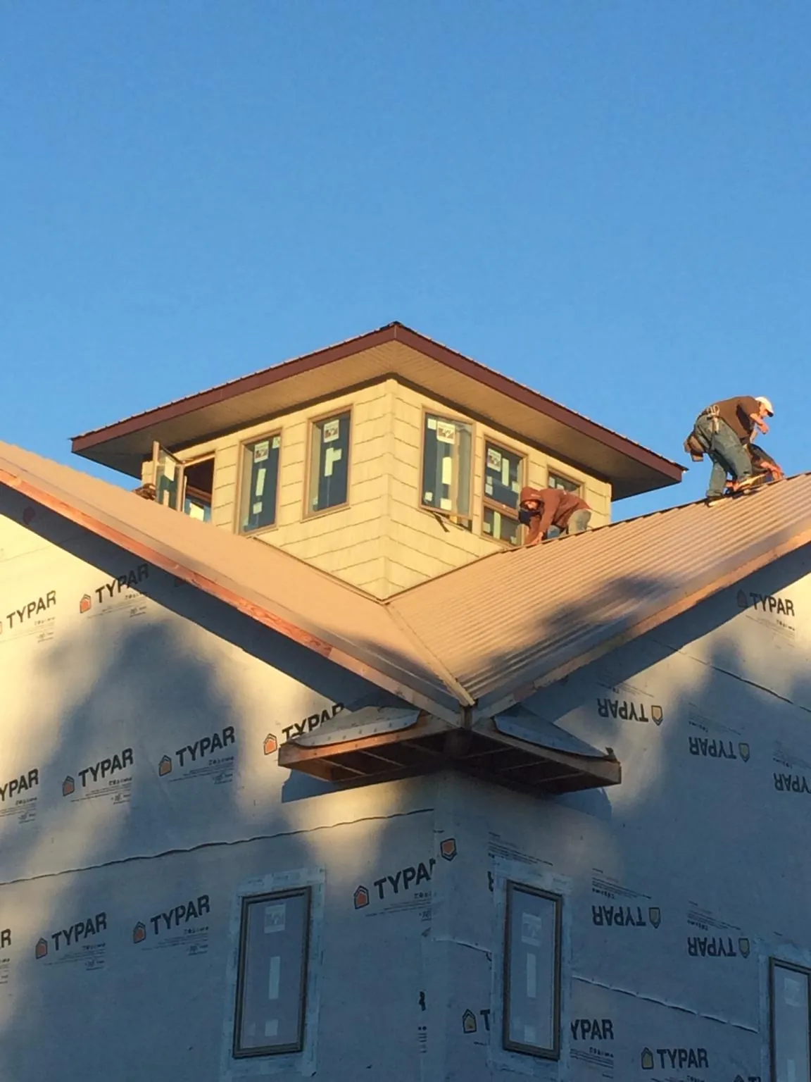 Roofers working around a rooftop cupola on a new metal roof at sunset — Roof Waterproofing in Holyoke by Roofing Brothers